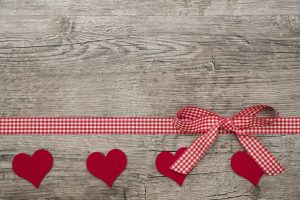 Red hearts with ribbon gift on wooden background